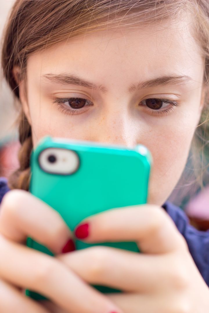 Extreme close-up of girl texting on her handheld mobile cell phone with focus on eyes.