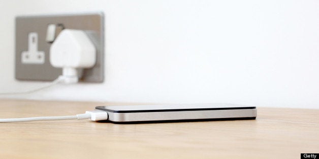 Silver and black Mobile phone being charged on wooden surface