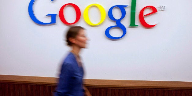 A Google Inc. employee walks past a logo outside the entrance to the company's offices in Berlin, Germany, on Friday, Aug. 16