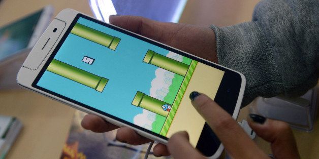 An employee plays the game Flappy Bird at a smartphone store in Hanoi on February 10, 2014. The Vietnamese developer behind the smash-hit free game Flappy Bird has pulled his creation from online stores after announcing that its runaway success had ruined his 'simple life'. AFP PHOTO/HOANG DINH Nam (Photo credit should read HOANG DINH NAM/AFP/Getty Images)
