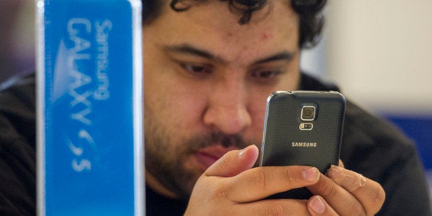 A customer looks at the new Samsung Electronics Co. Galaxy S5 smartphone on display at a Best Buy Co. store in San Francisco, California, U.S., on Friday, April 11, 2014. The S5 features a 5.1-inch screen with a fingerprint reader, 16-megapixel camera, heart-rate sensor, water-resistant coating that can withstand 30 minutes at the bottom of a meter-deep (3-foot deep) pond, and a back resembling dimpled leather. Photographer: David Paul Morris/Bloomberg via Getty Images