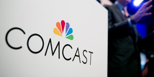 The Comcast Corp. logo is seen as Brian Roberts, chairman and chief executive officer of Comcast Corp., right, speaks during