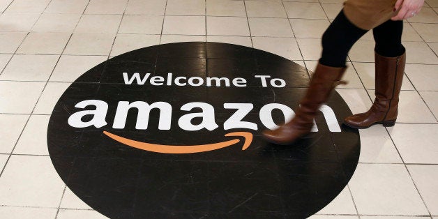 An employee walks over a logo on the floor of Amazon.com Inc.'s fulfillment centers in Rugeley, U.K., on Monday, Dec. 2, 2013