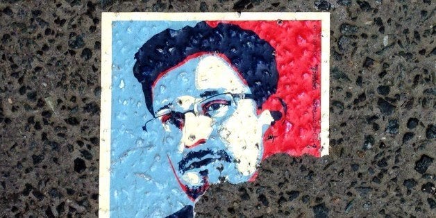 A sticker featuring fugitive US intelligence leaker Edward Snowden and partially reading 'asylum' is seen on the pavement in a Berlin street, on May 26, 2014. A German panel set up to assess the extent of spying by the US National Security Agency and its partners on German citizens and politicians, and whether German intelligence aided its activities, decided on May 21, 2014 it wants to question Snowden, perhaps via video link or by sending an envoy to Russia where he has been given temporary asylum. AFP PHOTO / ODD ANDERSEN (Photo credit should read ODD ANDERSEN/AFP/Getty Images)