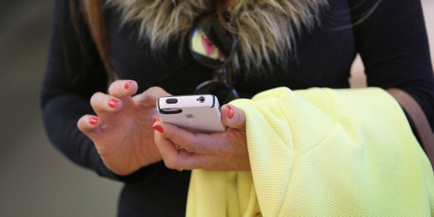 NEW YORK, NY - APRIL 22: A woman uses an Iphone at Apple's Fifth Avenue store on Earth Day in Midtown Manhattan on April 22, 2014 in New York City. The store is one of at least 120 Apple stores currently powered by renewable energy. To coincide with Earth Day, Apple announced it's offering free recycling of all of its used products. Employees wore green shirts for the occasion. (Photo by John Moore/Getty Images)