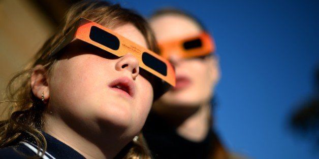 A child (L) watches a partial solar eclipse with a woman at the Sydney Observatory on May 10, 2013. Star-gazers were treated to an annular solar eclipse in remote areas of Australia with the Moon crossing in front of the Sun and blotting out much of its light. The annular eclipse, a phenomenal which occurs when the Moon is so close to the Earth that is cannot completely cover the Sun when it passes between it, was seen across a band across northern Australia, while places such as Sydney saw a partial eclipse. AFP PHOTO / Saeed KHAN (Photo credit should read SAEED KHAN/AFP/Getty Images)
