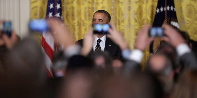 WASHINGTON, DC - JANUARY 23: Obsucred by guests' mobile phone cameras, U.S. President Barack Obama delivers remarks before taking questions during a reception for about 250 mayors from across the country in the East Room of the White House January 23, 2014 in Washington, DC. The U.S. Conference of Mayors is holding its winter meeting in Washington this week. (Photo by Chip Somodevilla/Getty Images)