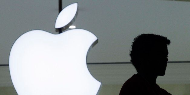 A person stands near the Apple logo at the company's new store in Grand Central Terminal, Wednesday, Dec. 7, 2011 in New York. (AP Photo/Mark Lennihan)