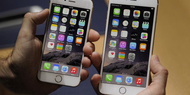 An attendee displays the new Apple Inc. iPhone 6, left, and iPhone 6 Plus for a photograph after a product announcement at Flint Center in Cupertino, California, U.S., on Tuesday, Sept. 9, 2014. Apple Inc. unveiled redesigned iPhones with bigger screens, overhauling its top-selling product in an event that gives the clearest sign yet of the company's product direction under Chief Executive Officer Tim Cook. Photographer: David Paul Morris/Bloomberg via Getty Images