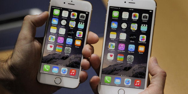 An attendee displays the new Apple Inc. iPhone 6, left, and iPhone 6 Plus for a photograph after a product announcement at Flint Center in Cupertino, California, U.S., on Tuesday, Sept. 9, 2014. Apple Inc. unveiled redesigned iPhones with bigger screens, overhauling its top-selling product in an event that gives the clearest sign yet of the company's product direction under Chief Executive Officer Tim Cook. Photographer: David Paul Morris/Bloomberg via Getty Images