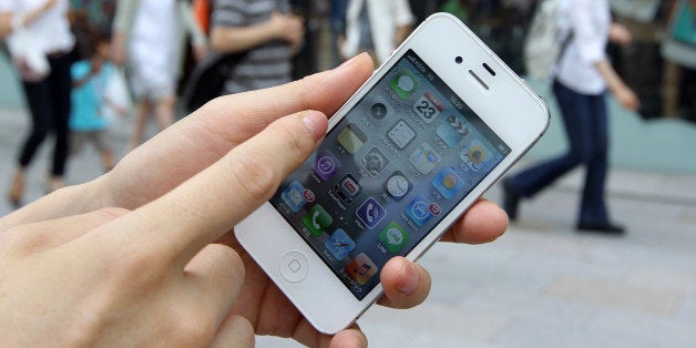 A woman holds her Apple Inc. iPhone for a photograph in front of the company's store in the Ginza district of Tokyo, Japan, on Sunday, June 23, 2013. Samsung and Apple, the worlds two biggest smartphone makers, have each scored victories in patent disputes fought over four continents since the maker of the iPhone accused Asias biggest electronics maker of slavishly copying its devices. Photographer: Koichi Kamoshida/Bloomberg via Getty Images