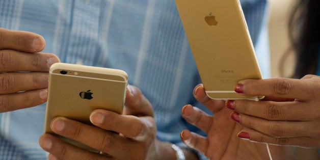 Customers compare an Apple Inc. iPhone 6, left, and iPhone 6 plus during the sales launch at an Apple store in Palo Alto, California, U.S., on Friday, Sept. 19, 2014. Apple Inc.'s stores attracted long lines of shoppers for the debut of the latest iPhones, indicating healthy demand for the bigger-screen smartphones. The larger iPhone 6 Plus is already selling out at some stores across the U.S. Photographer: David Paul Morris/Bloomberg via Getty Images