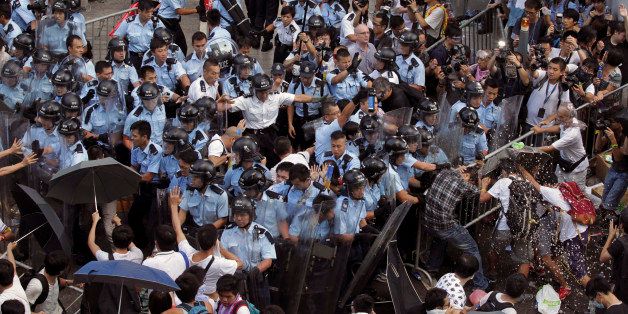 Riot policemen stand guard against protesters after young pro-democracy activists forced their way into Hong Kong government headquarters during a demonstration in Hong Kong, early Saturday, Sept. 27, 2014. The scenes of disorder came at the end of a weeklong strike by students demanding Chinaâs communist leaders allow residents to directly elect a leader of their own choosing in 2017. (AP Photo/Apple Daily) HONG KONG OUT, TAIWAN OUT