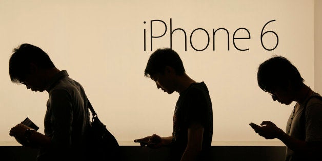 In this photo taken on Friday, Sept. 19, 2014, people wait to buy the new Apple iPhone 6 and 6 Plus devices outside an Apple