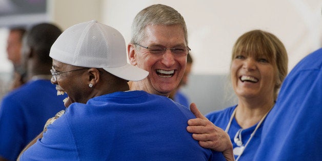 Tim Cook, chief executive officer of Apple Inc., center, hugs an employee during the sales launch for the iPhone 6 and iPhone