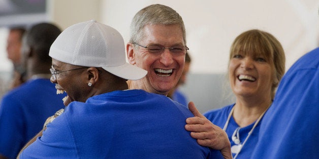 Tim Cook, chief executive officer of Apple Inc., center, hugs an employee during the sales launch for the iPhone 6 and iPhone 6 Plus at the Apple Inc. store in Palo Alto, California, U.S., on Friday, Sept. 19, 2014. Apple Inc.'s stores attracted long lines of shoppers for the debut of the latest iPhones, indicating healthy demand for the bigger-screen smartphones. The larger iPhone 6 Plus is already selling out at some stores across the U.S. Photographer: David Paul Morris/Bloomberg via Getty Images 