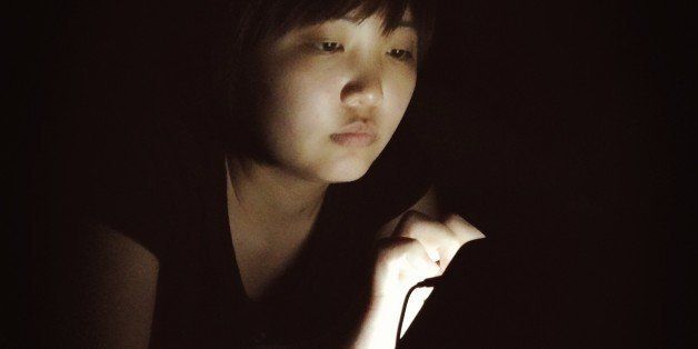 Teen on computer tablet at night