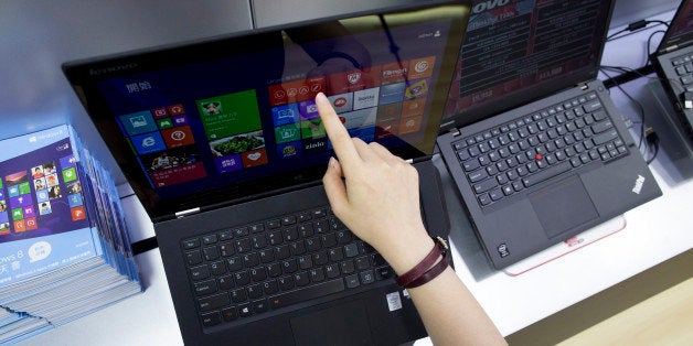 A woman uses a touch screen on a Lenovo Group Ltd. Yoga 2 Pro laptop in an arranged photograph at a Lenovo store in the Yuen Long district of Hong Kong, China, on Friday, May 23, 2014. Lenovo, the world's largest maker of personal computers, reported a 25 percent jump in fourth-quarter profit as its desktop models and mobile devices gained global market share. Photographer: Brent Lewin/Bloomberg via Getty Images