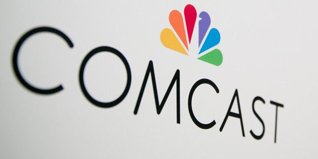 The Comcast Corp. logo is seen as Brian Roberts, chairman and chief executive officer of Comcast Corp., right, speaks during