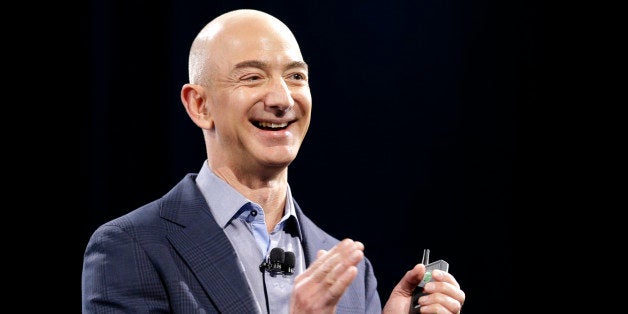 Amazon CEO Jeff Bezos holds a slide show controller and applauds at the start of the launch event for the new Amazon Fire Pho