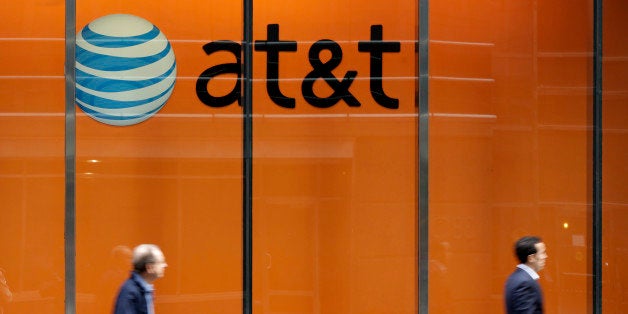 In this Tuesday, Oct. 21, 2014 photo, people pass an AT&T store on New York's Madison Avenue. AT&T says it will buy Mexican wireless company Iusacell for $2.5 billion including debt and says it plans to grow in Mexico. (AP Photo/Richard Drew)