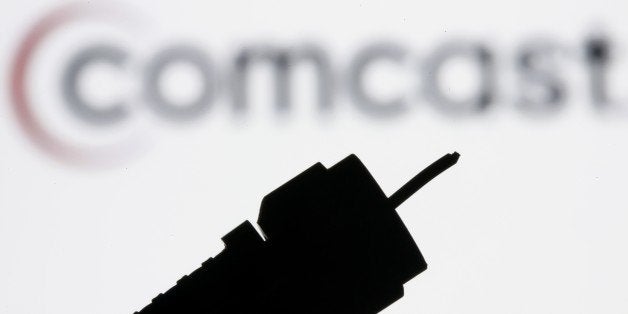 FILE - In this July 30, 2008 file photo illustration, a silhouetted coaxial cable is photographed with the Comcast Corp. logo