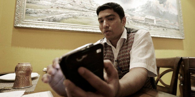 Bigyan Bhandari, a 28-year-old Nepalese who works at a Nepalese restaurant run by K.P. Sitoula, uses his smartphone to call his family members in Kathmandu during an interview in Seoul, South Korea Monday, April 27, 2015. Bhandari said he was finally able to talk with his loved ones in Kathmandu after dozens of unsuccessful attempts to call them. "I miss my family members ... too much," he said, tears welling in his eyes. (AP Photo/Ahn Young-joon)