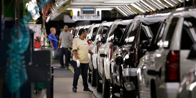 FILE - In this May 13, 2014 file photo, an auto worker inspects finished SUVs coming off the assembly line at the General Mot