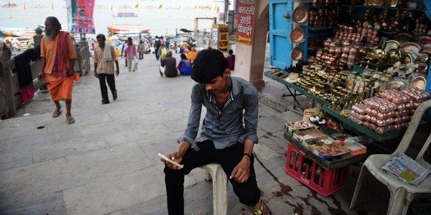 To go with ' India-Politics-Modi' FOCUS by Bhuvan BAGGAIn this photograph taken on May 10, 2015, Indian stallholder Ritesh Kumar tries to connect to a wi-fi network using his smartphone at Dashashwamed Ghat on the River Ganges in Varanasi. Narendra Modi marks the first anniversary of his landslide election win in a bullish mood about his mission to transform India into a great power, despite doubts about the delivery of economic reforms. After winning the first outright majority by any leader in three decades on May 16, 2014, Modi vowed 'to make the 21st century India's century' and turn it into a driver of the global economy. AFP PHOTO/SANJAY KANOJIA (Photo credit should read Sanjay Kanojia/AFP/Getty Images)