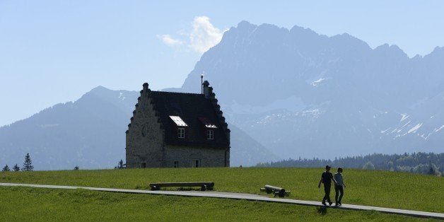 Hikers walk past a building of hotel Kranzbach in the Alp mountains in Elmau near Garmisch-Partenkirchen, southern Germany, o