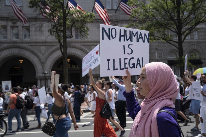 A demonstrator in Washington, D.C., holds a sign reading "No Human Is Illegal" while marching past the Trump International Hotel during a protest against the president's immigration policies.