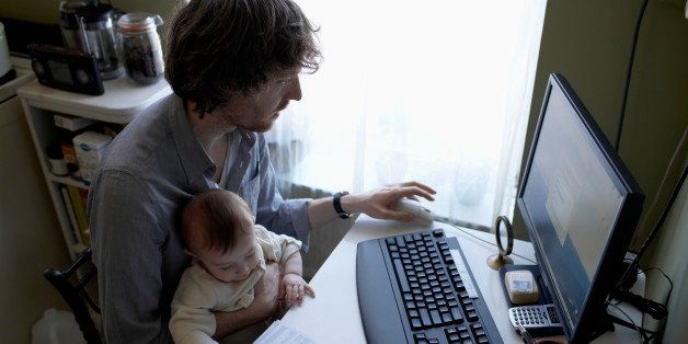 Father with baby boy (6-11 months) at table using computer, high angle view