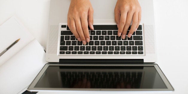 Hands typing on laptop computer, high angle view