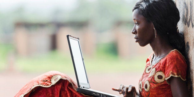 Street Shot of an African Ethnicity young woman working on business holding her technology item computer in a university in Bamako, Mali. Blurred background. University high school environment.