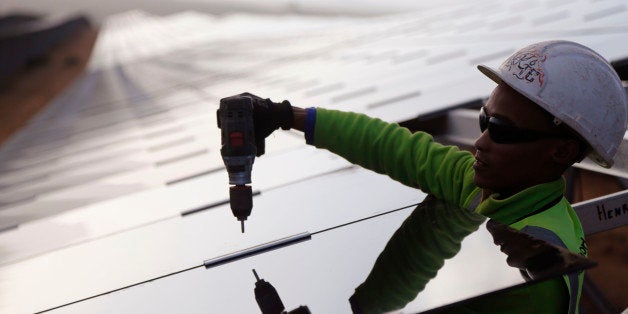 A worker installs a solar panel at a photovoltaic solar park situated on the outskirts of the coastal town of Lamberts Bay, South Africa, Tuesday, March. 29, 2016. Italian company TerniEnergia, started the solar park making use of a photovoltaic process that converts light into electricity through panels, with the facility expected to produce up to 75 Megawatts, to be connected to the South African electric grid. (AP Photo/Schalk van Zuydam)