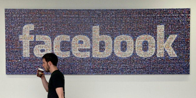 FILE - In this March 15, 2013, file photo, a Facebook employee walks past a sign at Facebook headquarters in Menlo Park, Calif. Facebook reports financial results on Wednesday, April 27, 2016. (AP Photo/Jeff Chiu, File)