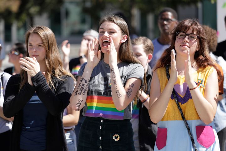 Azusa Pacific University students Alissa Gmyrek, Cayla Hailwood and Rachel Davis cheer at a rally to protest the school's reinstated ban on same-sex relationships on campus.