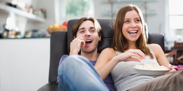 Couple watching television and eating popcorn