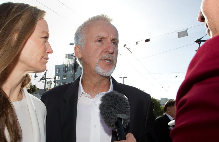 Director James Cameron (C) and Suzy Amis (L) speak to the media upon their arrival at the world premiere of 'The Hobbit' movi