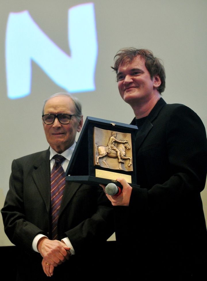 US director QuentinTarantino (R) poses after received a lifetime career prize from Italian composer Ennio Morricone (L), on behalf of the Rome film festival, on January 4, 2013 in Rome at the premiere of his latest film 'Django Unchained' -- a homage to Italian-made cowboy movies from the 1960s. AFP PHOTO / TIZIANA FABI (Photo credit should read TIZIANA FABI/AFP/Getty Images)