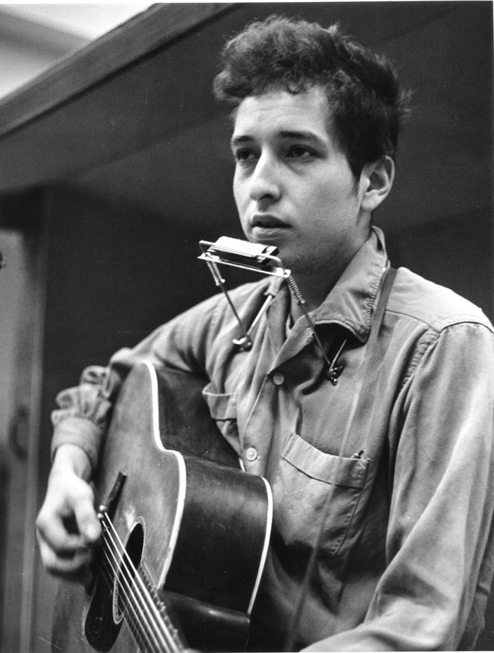 NOVEMBER 1961: Bob Dylan recording his first album, 'Bob Dylan', in front of a microphone with an acoustic Gibson guitar and a harmonica during one of the John Hammond recording sessions in November 1961 at Columbia Studio in New York City, New York. (Photo by Michael Ochs Archives/Getty Images)