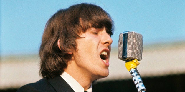 British singer, composer and musician George Harrison playing guitar and singing during the concert of British band The Beatl