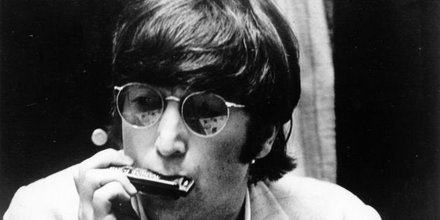 22nd June 1966: Beatles singer, songwriter and guitarist John Lennon (1940 - 1980) plays the harmonica, his guitar rested on his knee. (Photo by Keystone Features/Getty Images)