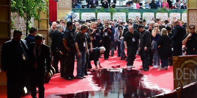 Staff clean up water on the red carpet of the Golden Globe awards in Beverly Hills on January 12, 2014 after a pipe burst before the start of the event. AFP PHOTO / Frederic J. Brown (Photo credit should read FREDERIC J. BROWN/AFP/Getty Images)