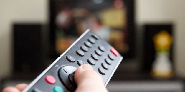 Human hand holding remote control changing Channels with television set.