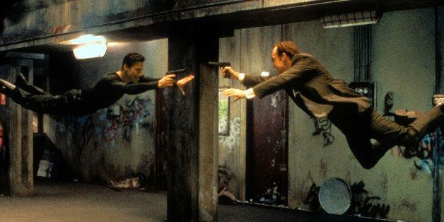 Keanu Reeves and Hugo Weaving pointing guns at each other in a scene from the film 'The Matrix', 1999. (Photo by Warner Brothers/Getty Images)