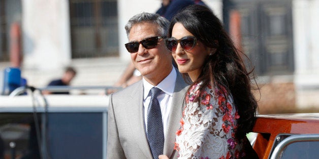 George Clooney is flanked by his wife Amal Alamuddin as they leave the Aman luxury Hotel in Venice, Italy, Sunday, Sept. 28, 2014. George Clooney married human rights lawyer Amal Alamuddin Saturday, the actor's representative said, out of sight of pursuing paparazzi and adoring crowds. (AP Photo/Luca Bruno)