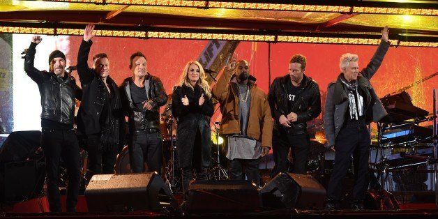 (L-R) The Edge, Larry Mullen Jr., Bruce Springsteen, Carrie Underwood, Kayne West, Coldplays Chris Martin and Adam Clayton of U2 greet the audience during the World AIDS Day (RED) concert in Times Square in New York on December 1, 2014. RED is an organization that aims to prevent HIV transmission from mother to child. AFP PHOTO / Timothy A CLARY (Photo credit should read TIMOTHY A. CLARY/AFP/Getty Images)