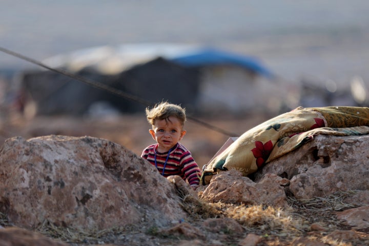 A newly displaced Syrian child walks near a refugee camp