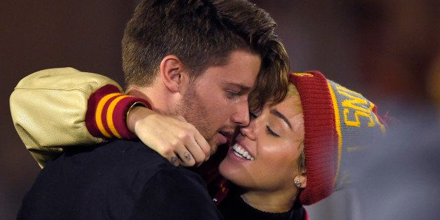 Singer Miley Cyrus, right, puts an arm around Patrick Schwarzenegger as they watch Southern California play California during the second half of an NCAA college football game, Thursday, Nov. 13, 2014, in Los Angeles. (AP Photo/Mark J. Terrill)